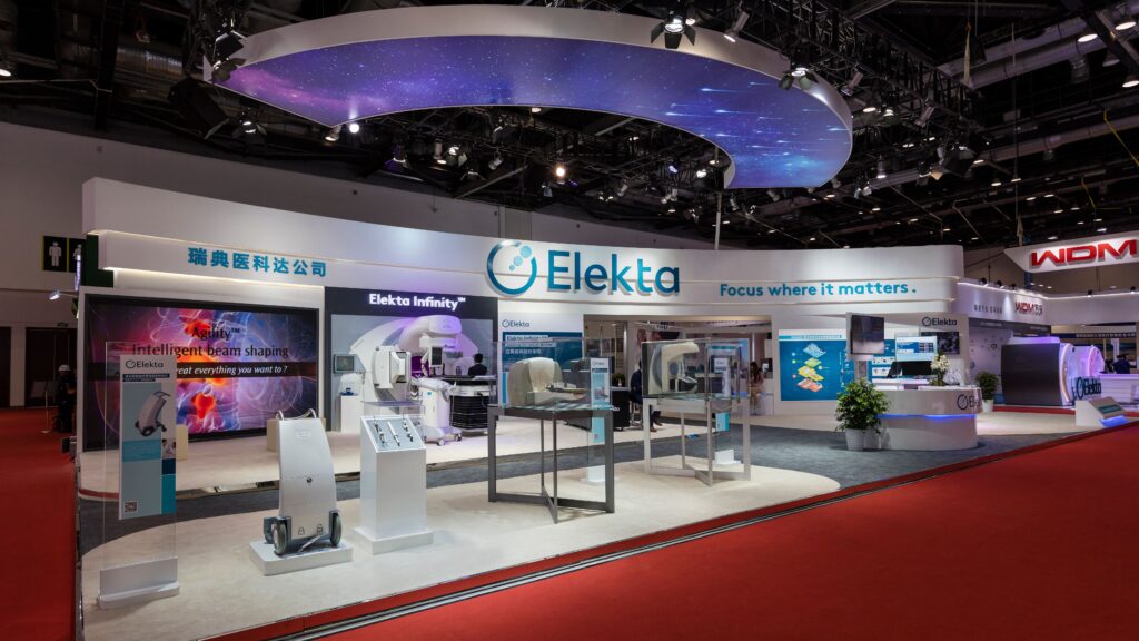 未来的なデザイン展示会ブースで、LED照明や大型デザインパネルを活用し、洗練されたブランドイメージを伝えている。