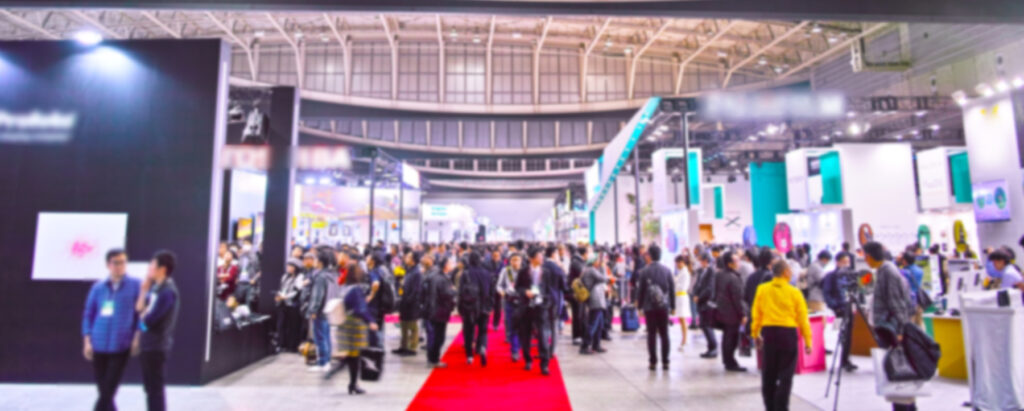大規模な展示会の会場風景。多数の来場者と企業のブースで賑わっている様子。