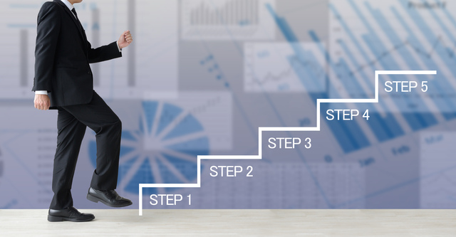 スーツを着たビジネスマンが、「STEP 1」から「STEP 5」と書かれた階段を上っている。背景にはグラフやデータがあり、進捗や目標達成のイメージ。
